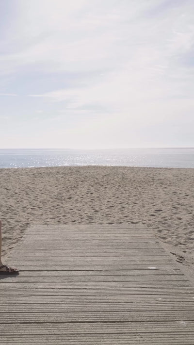 Mujer luciendo sandalias planas Porronet y bolso capazo de playa durante un paseo de verano.